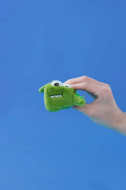 Hand holding a Mini Crocodile plush toy against a blue background, showcasing its squishy design and fun features.
