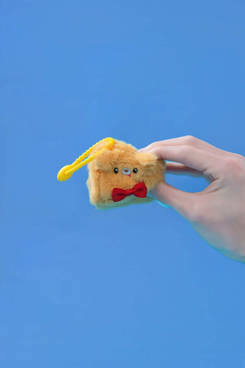 Mini dog squishy plush toys held in hand with a yellow clip and cute bow tie.
