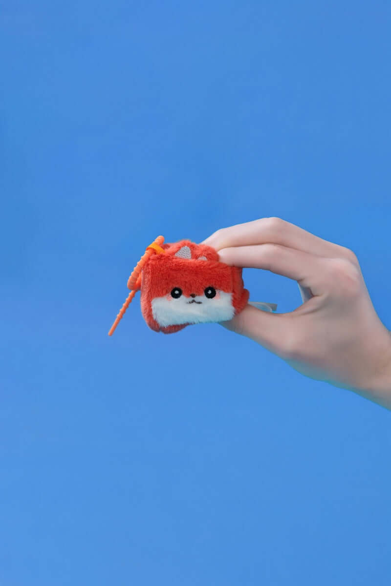 Mini Fox collectible plush toy being held against a blue background, showcasing its squishy features.