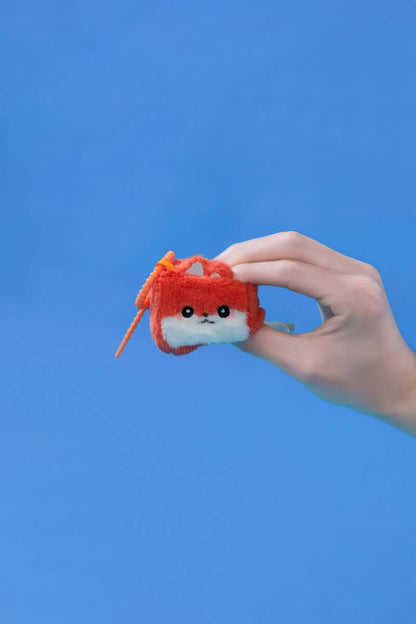 Mini Fox collectible plush toy being held against a blue background, showcasing its squishy features.